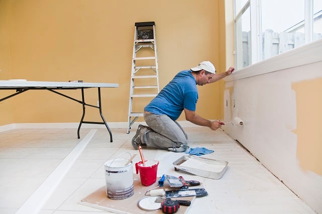 man painting yellow wall white